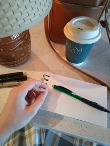 notebook and pen sitting on a table with a coffee cup